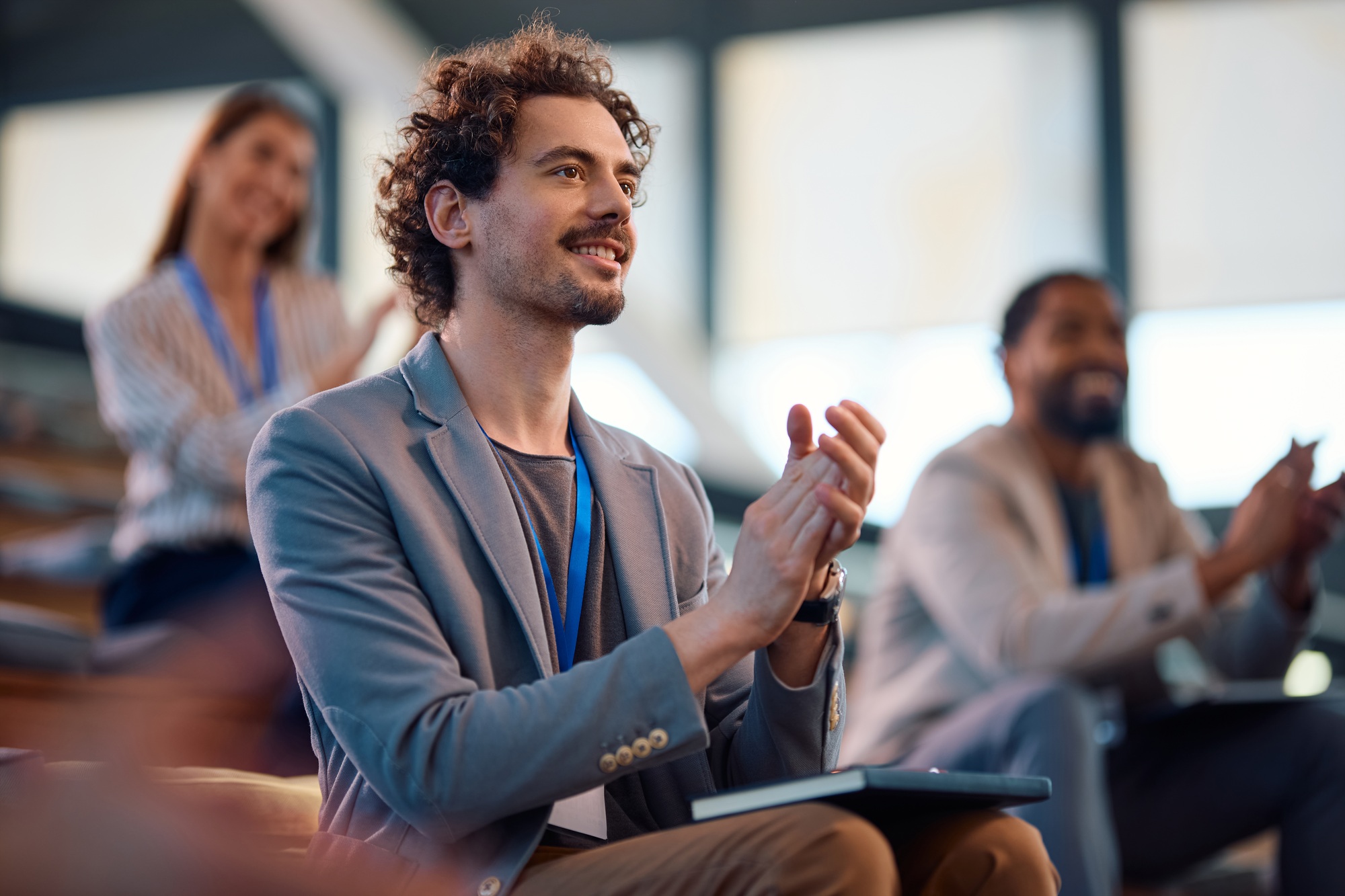 Happy entrepreneur applauding after successful business seminar in conference hall.